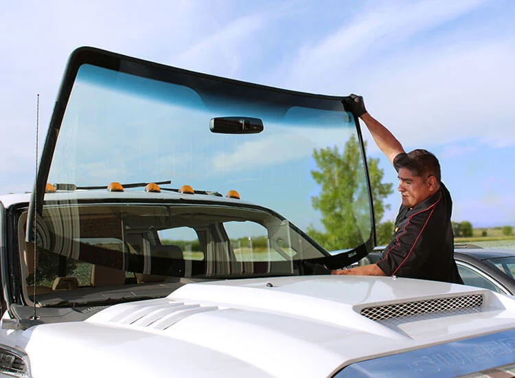 A technician replacing a truck's front windshield